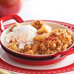 a bowl filled with fruit and ice cream on top of a red plate next to an apple