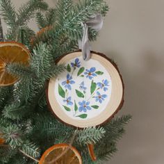 an ornament is hanging on a tree with orange slices and blue flowers in it