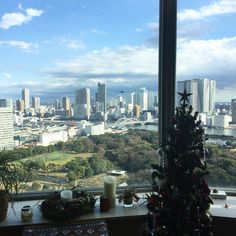 a christmas tree sitting on top of a window sill in front of a city