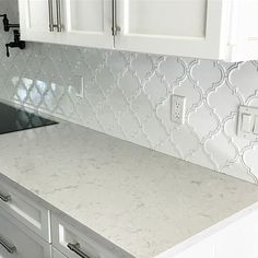 a kitchen counter with white cabinets and tile backsplash