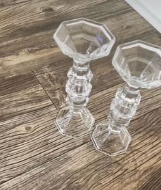 two clear glass candlesticks sitting on top of a wooden table