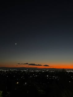 the sun is setting over a city with trees and buildings in the foreground at night