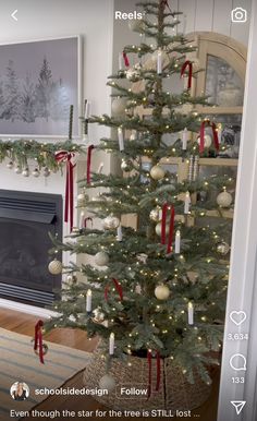 a decorated christmas tree in front of a fireplace with red and white ribbon on it