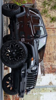 an suv is upside down on the side of a building with two tires hanging from it's roof