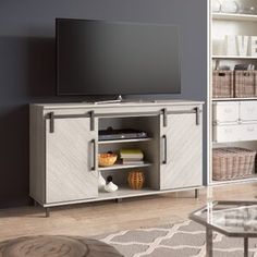 an entertainment center with a large flat screen tv on it's stand and wicker baskets