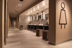 a bathroom with several sinks and mirrors on the wall, along with lights above them