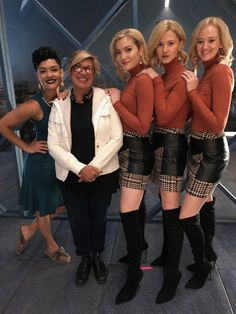 four women in short skirts and boots posing for the camera