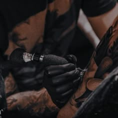 a man with tattoos on his arm holding a microphone in one hand and wearing black gloves