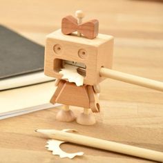 a wooden toy with a bow tie on it's head standing next to an open book