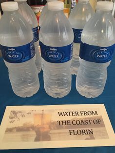 four bottled water bottles sitting on top of a table next to a sign that says water from the coast of florin