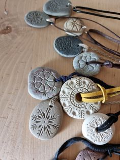 several necklaces are laid out on a wooden table with beads and cords hanging from them