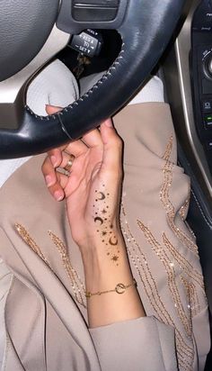 a woman with tattoos on her arm holding onto a black leather handbag while sitting in a car