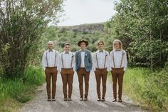 a group of young men standing next to each other on a dirt road with trees in the background