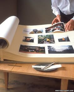 a man is holding an open book on a table with photos and papers in it