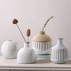 three white vases sitting on top of a table