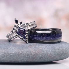 two rings are sitting on top of a rock and one has a blue stone in the middle