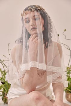 a woman wearing a veil and sitting on the ground with her hands under her chin