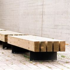 a wooden bench sitting on top of a brick floor next to a wall and grass