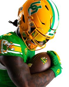 a football player wearing a green and yellow uniform with his hands on his chest, holding a football