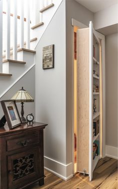 an open door leading to a room with stairs and bookshelves in the corner