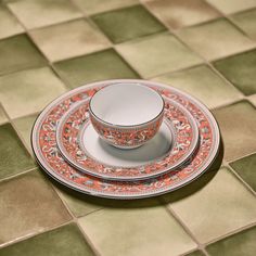 a cup and saucer sitting on top of a plate in front of a tiled floor