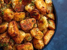 cooked potatoes with herbs and seasoning in a blue bowl on a blue tablecloth