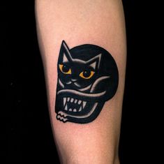 a black cat with yellow eyes and fangs on its face is shown in this tattoo design