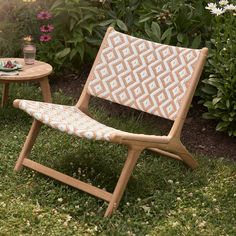 a lawn chair sitting in the grass next to a small table with flowers on it