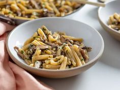 a white bowl filled with pasta and mushrooms on top of a table next to other dishes