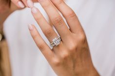 a woman's hand with a diamond ring on her left hand and the other hand holding an engagement ring