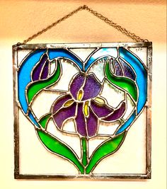 a heart shaped stained glass window hanging on a wall with flowers in the shape of a flower