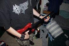 a young man holding a red electric guitar