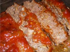 meatloaf with sauce and cheese on top in an oven pan, ready to be cooked