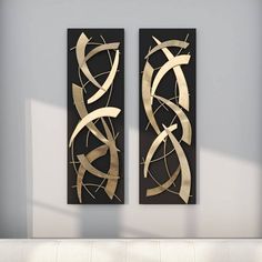 two metal art pieces hanging on the wall next to a white couch in a living room