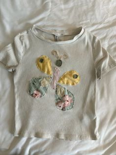 a white t - shirt with a butterfly applique on it