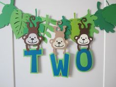 three monkeys hanging from the side of a wall next to some cut out letters that spell out two