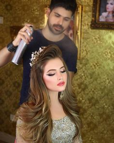 a woman getting her hair done by a man in a room with gold wallpaper