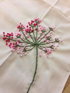 pink and white flowers are embroidered onto the linen on this tablecloth, which has been stitched together