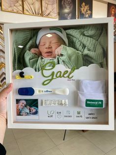 a hand holding up a framed photo of a baby