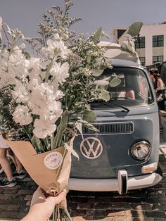 a person holding a bouquet of flowers in front of a vw van