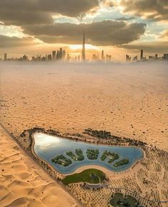 an aerial view of a city and lake in the middle of sand dunes with skyscrapers in the background