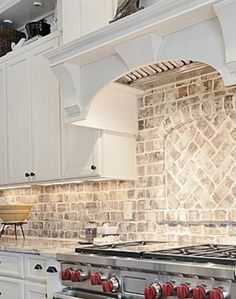 a kitchen with white cabinets and stone backsplashing on the stove top oven