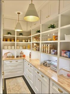 a kitchen filled with lots of white cupboards and counter top space next to a light fixture