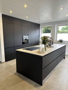 a modern kitchen with black cabinets and white counter tops, an island in the middle