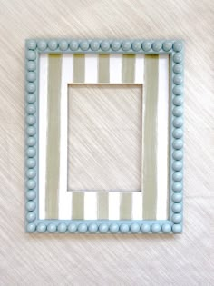 a blue and white striped frame with beading around the edges on a beige background