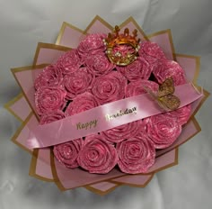 a bouquet of pink roses with a tiara on top and a happy birthday ribbon