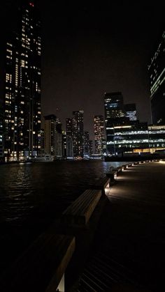 the city skyline is lit up at night with lights reflecting in the water and buildings along the waterfront