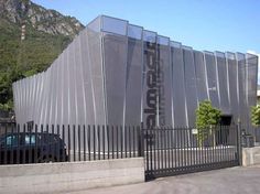 a car is parked in front of a building that has a fence on the side