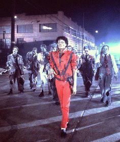 a group of people walking across a street next to each other in the night time