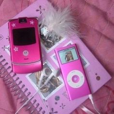 a pink cell phone sitting on top of a table next to an ipod and mp3 player